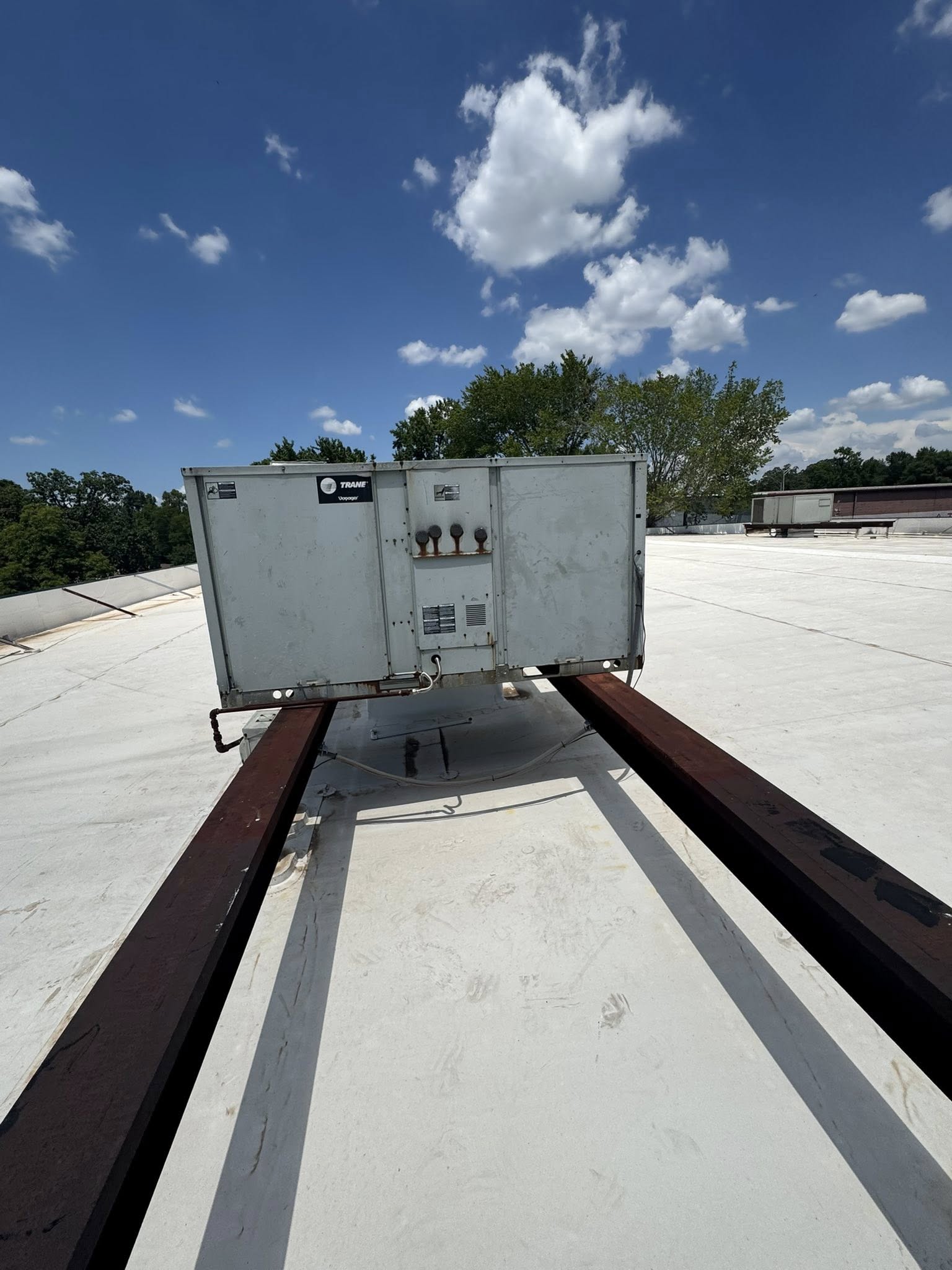 Trane rooftop HVAC unit mounted on steel rails on a flat commercial roof