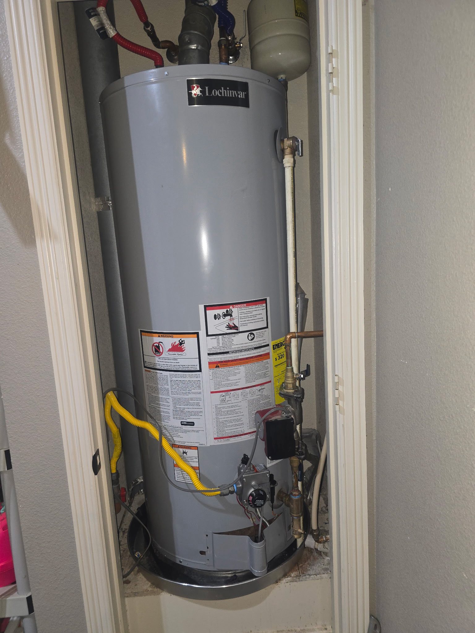 Lochinvar gas water heater installed in a closet with yellow gas line, copper pipes, and expansion tank above