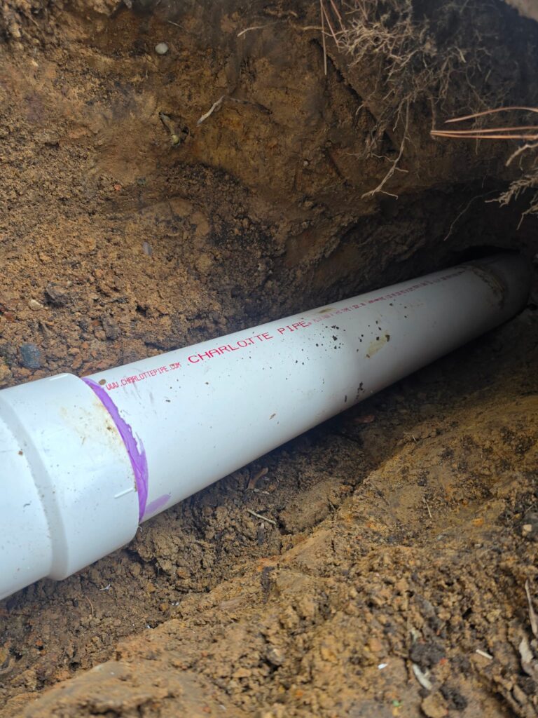 Charlotte Pipe PVC sewer pipe laid in an excavated trench during underground plumbing installation