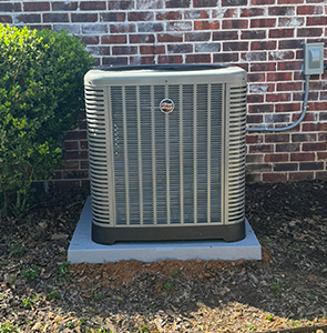 Outdoor central air conditioning unit installed on a concrete pad beside a brick house